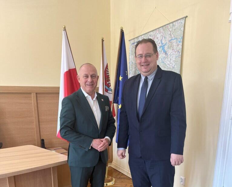 Dwie osoby stojące na tle flag.